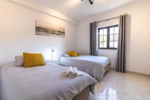 a bedroom with two beds and a window at La Familia House in São Teotónio