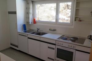 a white kitchen with a sink and a window at Apartment Scuol in Scuol