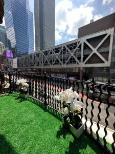 Une clôture avec des fleurs sur l'herbe dans une ville dans l'établissement TIME SQUARE 42nd Street Private Room, à New York