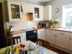 una cocina con armarios blancos y una mesa con frutas. en 3 Bed in Dymchurch 46913, en Littlestone-on-Sea