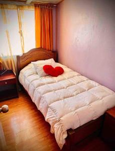 uma cama com uma almofada de coração vermelho em Cabaña con estacionamiento privado em Llanquihue