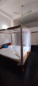 a bedroom with a bed with a mosquito net at Golden Lodge Tangalle in Tangalle