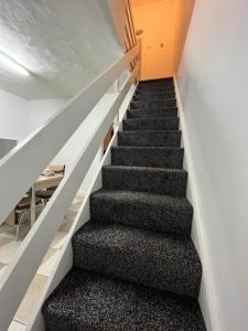 a staircase in a house with black carpet at Comfortable, spacious 2 Bedroom house close to Etihad Stadium in Stalybridge