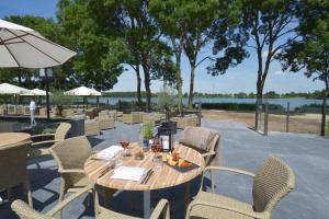 - une table en bois avec des chaises et un parasol sur la terrasse dans l'établissement Fletcher Hotel-Restaurant ‘s-Hertogenbosch, à Bois-le-Duc