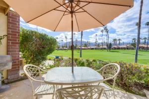 a table and chairs with an umbrella and a golf course at Stunning Palm Desert Condo with Golf Course Views! in Palm Desert