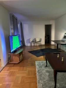 ein Wohnzimmer mit einem Flachbild-TV und einem Tisch in der Unterkunft Home Stays-Private Rooms in a Villa Near City for families/Individuals in Stockholm