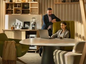 Ein Mann und eine Frau sitzen an einem Tisch mit einem Laptop in der Unterkunft Novotel Paris Coeur d'Orly Airport in Orly