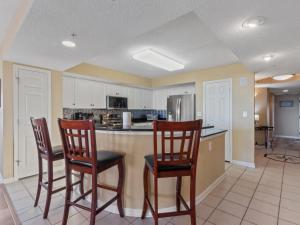 een keuken met 3 stoelen en een aanrecht met een koelkast bij Yacht Club Villas #1- 1005 condo in Myrtle Beach