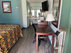 a hotel room with a bed and a desk and a mirror at Nola Inn in Slidell
