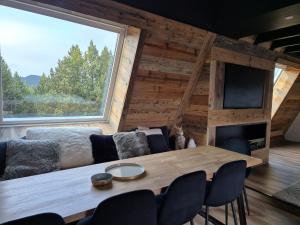 a dining room with a table and a large window at A l'orée des bois in Les Angles