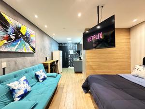 een slaapkamer met een blauwe bank en een tv bij Rover Centro in Sao Paulo