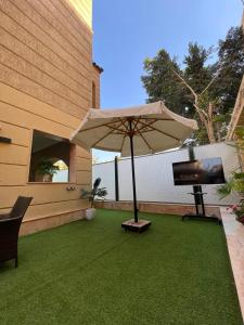 a patio with an umbrella and a television on the grass at DownTown New Cairo in Cairo