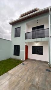 a white house with a red door at Triplex novo em Matinhos litoral Paraná in Matinhos