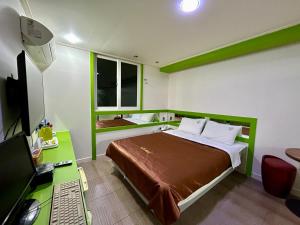 Schlafzimmer mit einem Bett und einem Schreibtisch mit einem Computer in der Unterkunft Two motel in Tongyeong