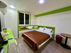 Schlafzimmer mit einem Bett und einem Schreibtisch mit einem Computer in der Unterkunft Two motel in Tongyeong