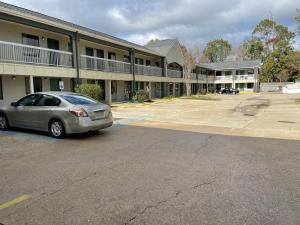 a car parked in a parking lot in front of a building at Nola Inn in Slidell