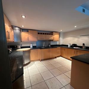a large kitchen with wooden cabinets and black counter tops at Canary Wharf Apartments in London