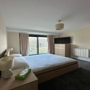 a bedroom with a large bed with a large window at Canary Wharf Apartments in London