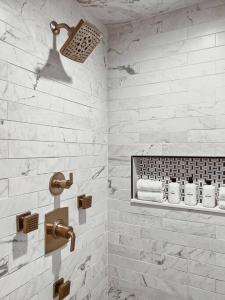 La salle de bains est pourvue de carrelage blanc, d'une douche et de serviettes. dans l'établissement Leo's Bear Lake Hideaway, à Kalkaska