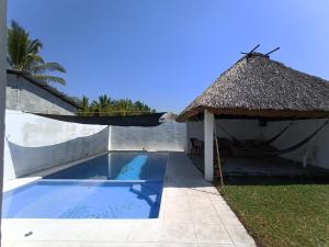 una piscina con sombrilla junto a una casa en CASA PARLAMAR en Monterrico