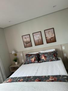 a bedroom with a bed with four pictures on the wall at Flat próximo ao Shopping Campo Grande in Campo Grande