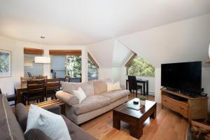 a living room with a couch and a flat screen tv at Gleneagle 29 - Townhome near Golf Course with Balcony, BBQ - Whistler Platinum in Whistler