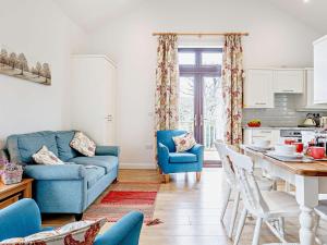 a living room with a blue couch and a kitchen at 2 Bed in Wellington 56950 in West Buckland