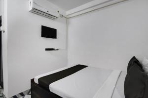 a bedroom with a bed and a tv on the wall at Super OYO PPS NEST Guest House in Kolkata