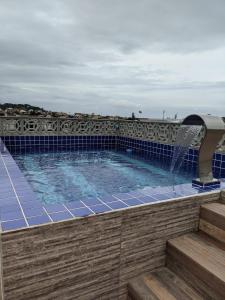 a swimming pool with a water fountain on a patio at Região dos Lagos - casa para temporada in São Pedro da Aldeia