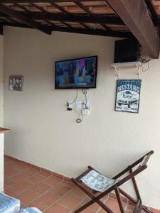 Região dos Lagos - casa para temporada في ساو بيدرو دا ألديا: كرسي وتلفزيون على جدار