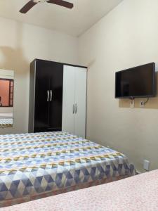 Região dos Lagos - casa para temporada في ساو بيدرو دا ألديا: غرفة نوم بسرير وتلفزيون بشاشة مسطحة