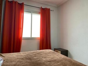 a bedroom with a bed and a window with red curtains at Oran in Oran
