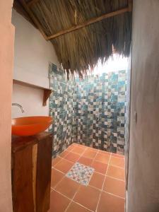 y baño con lavabo de color naranja y suelo de baldosa. en Cabaña Compartida en Calabazo - Celestial Villa Tayrona, en Santa Marta
