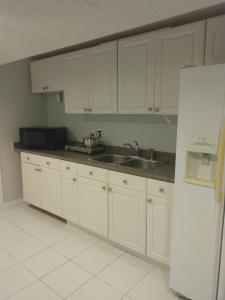 密西沙加的住宿－Fully furnished basement studio apartment，厨房配有白色橱柜、水槽和冰箱。