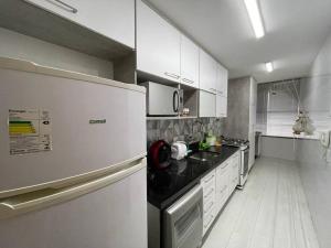  La cuisine est équipée de placards blancs et d'un réfrigérateur. dans l'établissement Vista Mar na Barra da Tijuca, à Rio de Janeiro
