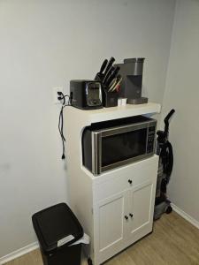 a microwave on a white shelf with a vacuum at Cozy and quiet apartment in Sudbury
