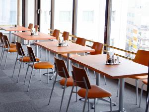 a row of tables and chairs in a room with windows at Hotel Abest Nagano Ekimae in Nagano