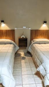 1 dormitorio con 2 camas y suelo de baldosa en Hospedaje Los Ilustres en Tunuyán