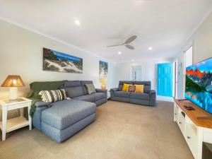 a living room with a couch and a flat screen tv at Bokarina Family Pet Friendly Holiday Home in Kawana Waters