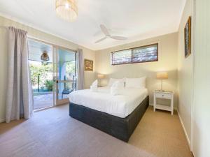 a bedroom with a white bed and a window at Bokarina Family Pet Friendly Holiday Home in Kawana Waters