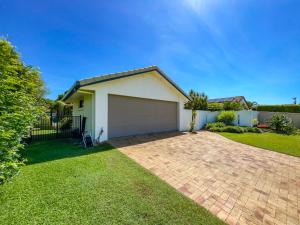 a house with a garage in a yard at Bokarina Family Pet Friendly Holiday Home in Kawana Waters