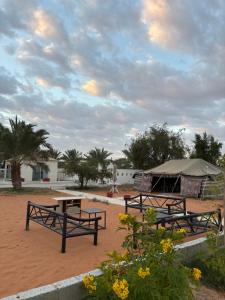 dos mesas de picnic y una tienda en un campo de tierra en مزرعة واستراحة درب التوت, en Riad
