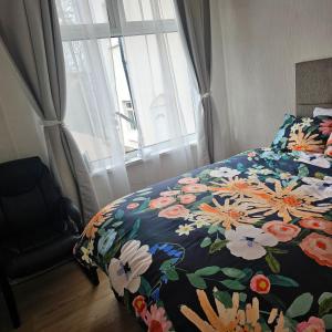 a bedroom with a bed with a floral comforter and a window at Bee hive 1 in Manchester