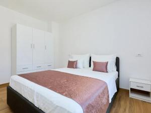 1 dormitorio con 1 cama blanca grande con almohadas rosas en Apartments by the sea Okuklje, Mljet - 22341, en Okuklje