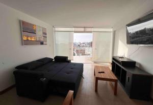uma sala de estar com um sofá preto e uma televisão em Apartamento exclusivo Familiar 306 em San Bartolo