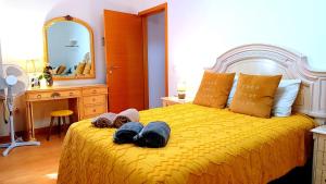 una camera da letto con un grande letto giallo con asciugamani di No centro, junto à Avenida da Liberdade - 1 Drt a Fundão