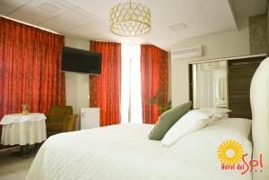 a bedroom with a large white bed and a table at Hotel del Sol in Tarija