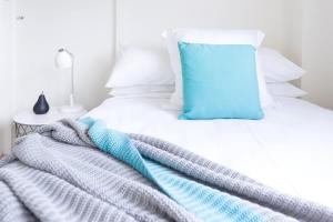 a white bed with a blue pillow on it at Live in the heart of Surry Hills - walk to City in Sydney