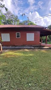 une maison rouge avec une cour d'herbe devant elle dans l'établissement Sitio Na Serra da Mantiqueira, à Piranguçu