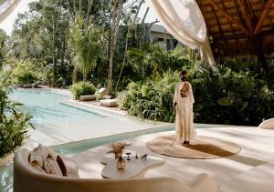 a woman is standing in front of a swimming pool at Hotel Milam in Tulum